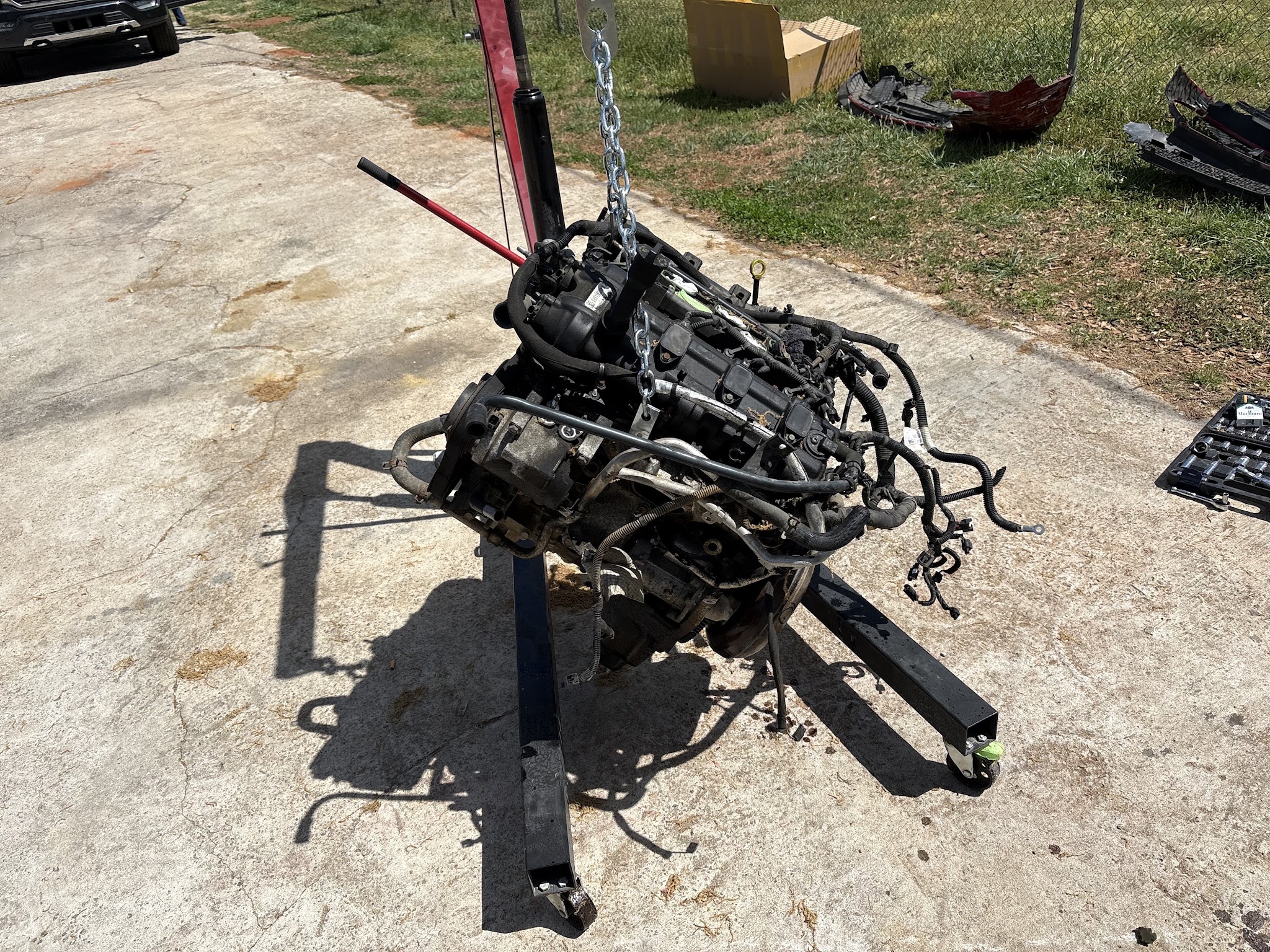 An engine hanging from an engine hoist outside