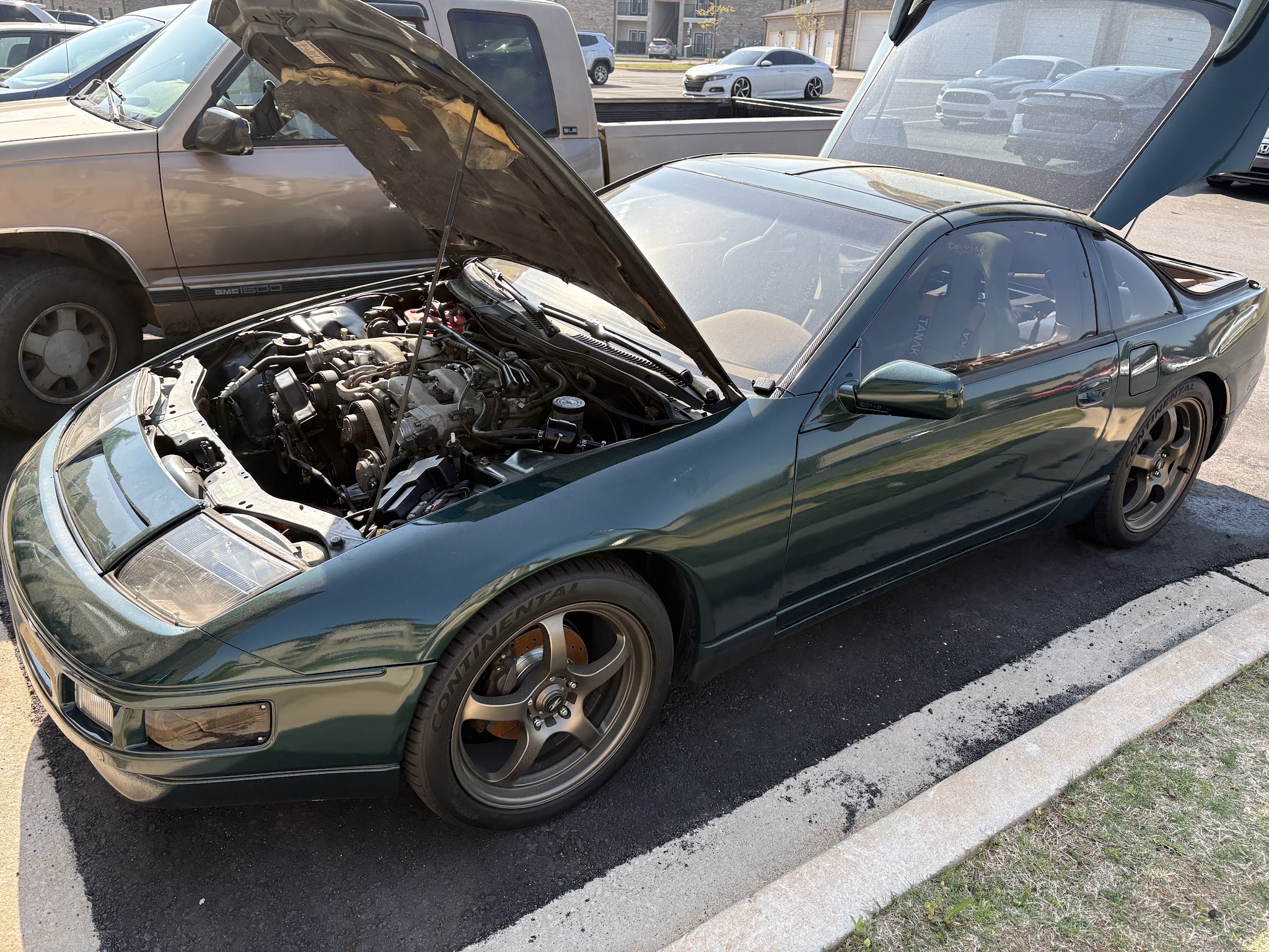 A green Nissan 300ZX with its hood up in a car park, mid-repair